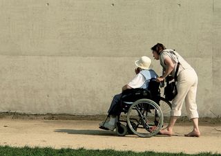 Ehrenamtliche schiebt Rollstuhl Ehrenamtliche schiebt Rollstuhl